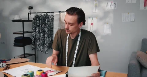 Man designer working in an atelier, choosing color fabrics for clothes design Stock Footage 220147084