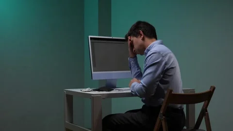 Man at a desk with a computer, looking into his empty wallet, experiencing Stock Footage 344604943