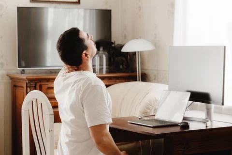 A man at a desk with a computer sips his neck Stockfoto's