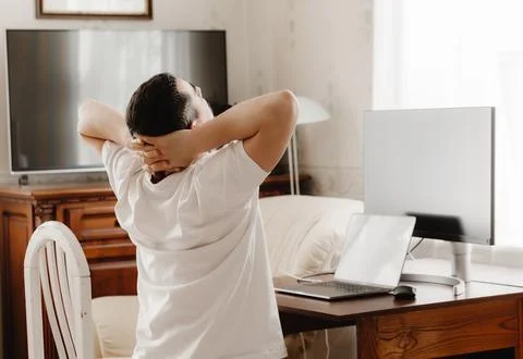 A man at a desk with a computer sips his neck Stockfoto's