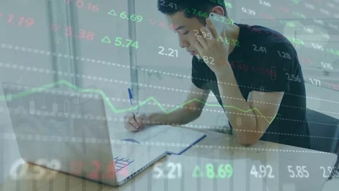 Man at desk responding to phone call and overlaid finance tickers, writing notes Stock Footage 335762084