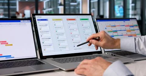 Man At Desk Using Software On Laptop To Organize Project Tasks Efficiently. Stock Photos