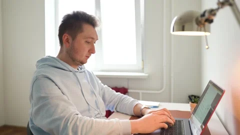 Man, desk, working on laptop, performs order, types message, next lamp is on Stock Footage 154842229