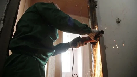 A man destroying old door frame with an angle grinder. Repairman, master Stock Footage 70913309