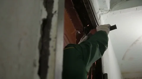 A man destroying old door frame with an angle grinder. Repairman, master Stock Footage 70913313