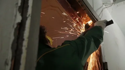 A man destroying old door frame with an angle grinder. Repairman, master Stock Footage 70913371