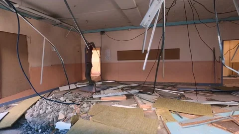 A Man Destroys the False Ceiling Of A Class Room before the Building Stock Footage 157462352