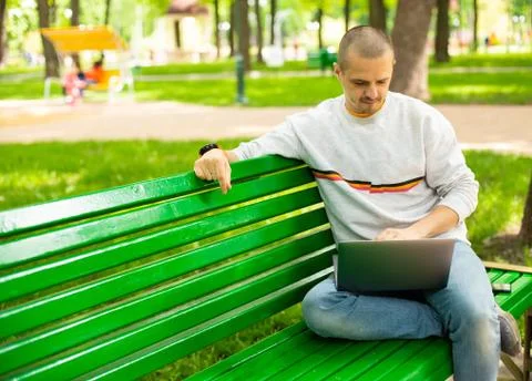 Man developer freelancer working outside sitting on bench Stock Photos
