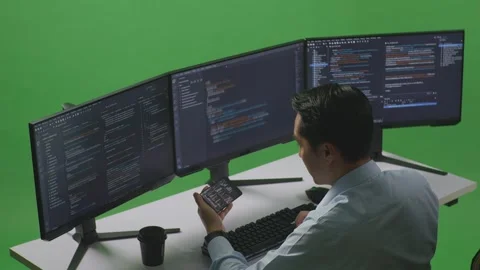 Man Developer Looking Code On Mobile While Write Code With Multiple Computer Stock Footage 249635343