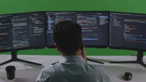 Man Developer Talking On Mobile Phone While Write Code With Multiple Computer Stock Footage 249632795