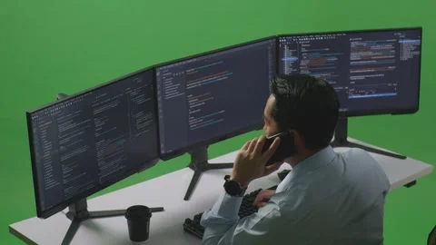 Man Developer Talking On Mobile Phone While Write Code With Multiple Computer Stock Footage 249635401