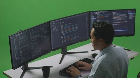 Man Developer Using Computer To Write Code With Multiple Screens In Green Stock Footage 249635044