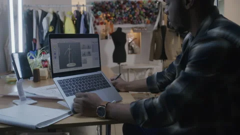 Man develops 3D clothes design on laptop in atelier Stock Footage 229734145