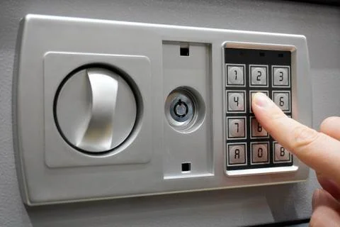 The man dials the code to close the safe. Grey safe closure, numeric keypad.  Foto stock