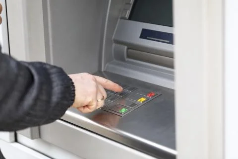 Man dials PIN code to withdraw money from ATM Stock Photos