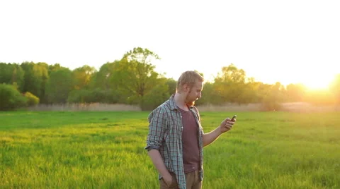 Man dials sms standing outdoors at sunset Video stock 63453048