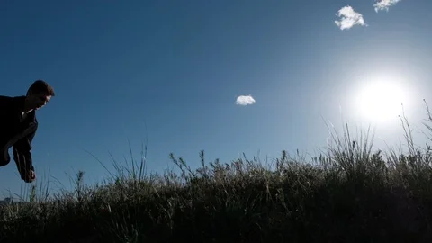 A man with difficulty climbs up the hill in the background of a cloudy sky Video stock 89348485