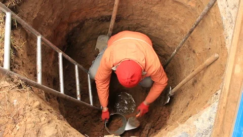 Man digger digs soil in a water well Stock Footage 165131585