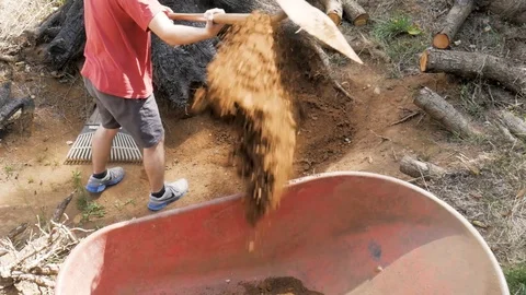 Man Digging and Tossing Dirt into a Wheel Barrel Stock Footage 115052629