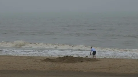 Man digging a big hole in the sea shore sand in order to build a castle Stock Footage 97948330