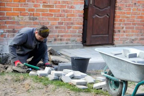 Man digging. Defocus Man examining a patio construction site, inspecting the Stock Photos