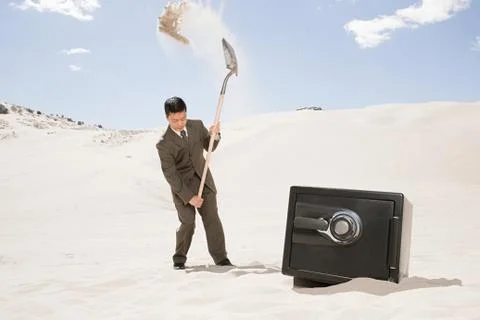 Man digging by safe in desert Stock Photos