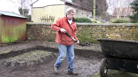 Man digging soil then carrying to wheelbarrow. Video stock 47086759