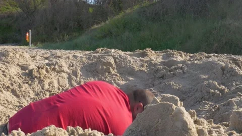A man digging through the sand for buried treasure - mid shot Stock Footage 133324545