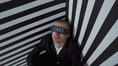 A man with digital goggles that say Psycho sitting in the corner of a room Video stock 258181869