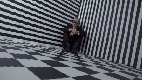 A man with digital goggles sitting in the corner of a room Vídeo Stock 258182484