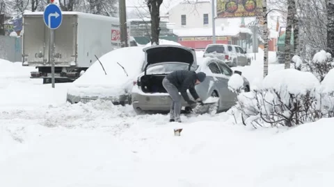 A man digs a car out of the snow Stock Footage 85487112