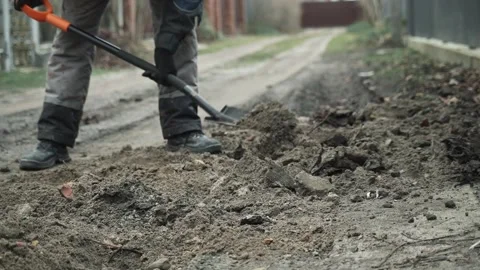 Man digs a ditch in the ground with a shovel Stock Footage 266806366