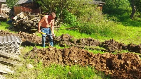 Man digs in garden while preparing soil for planting at rural location during su Stock Footage 329826702
