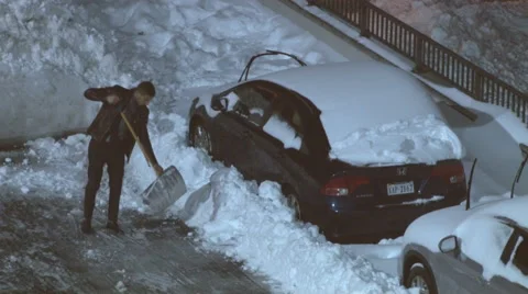 Man digs his parked car out of the snow. Stock Footage 59675599