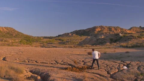 A man digs a hole in the ground with a shovel in a desert, in Spain Vídeos de archivo 208746553