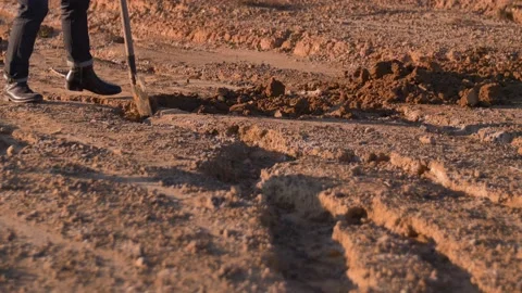 A man digs a hole in the ground with a shovel in a desert, in Spain Stock Footage 208808261