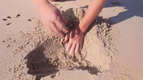 A man digs a hole in the sand with his hands, on the beach Stock Footage 330060947