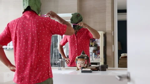 Man with dinosaur mask brushing teeth in bathroom. Stock Footage 199475259