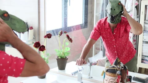 Man with dinosaur mask looking at himself in bathroom mirror. Stock Footage 200447552
