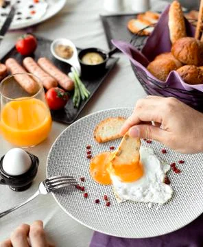 Man dipping roast into egg yellow for breakfast Stock Photos