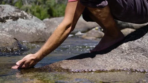 Man dips hand into stream Video stock 73489429