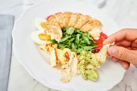 A man dips a piece of bread into hummus. Turkish breakfast with simit, cheese Stock Photos