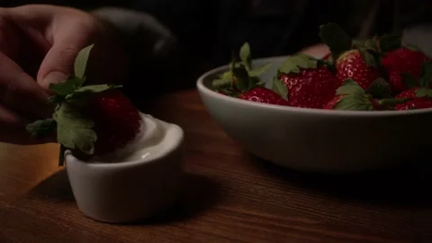A man dips strawberries in cream Stock Footage 223880835