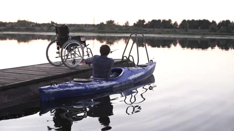 A man with a disability is kayaking against the backdrop of a golden sunset Stock Footage 239529922