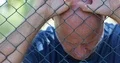 Man Disappointed and Disillusioned Hanging Desperate to a Metallic Fence 4k or 4k+ Resolution