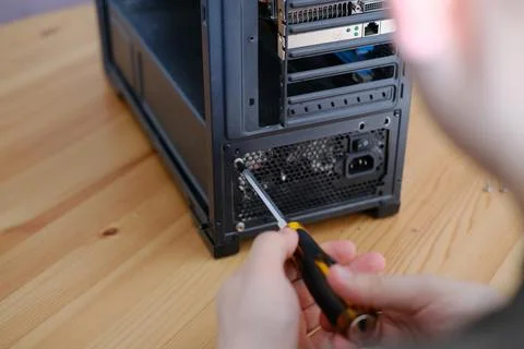 A man disassembles a computer system unit with a screwdriver Stock Photos