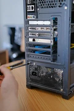 A man disassembles a computer system unit with a screwdriver Stock Photos