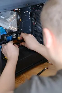 A man disassembles a computer system unit with a screwdriver Stockfoto's
