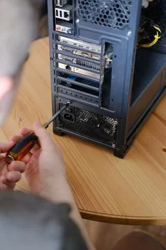 A man disassembles a computer system unit with a screwdriver Stock Photos