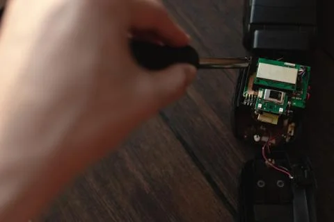 A man disassembles an electronic device with a screwdriver Stock Photos
